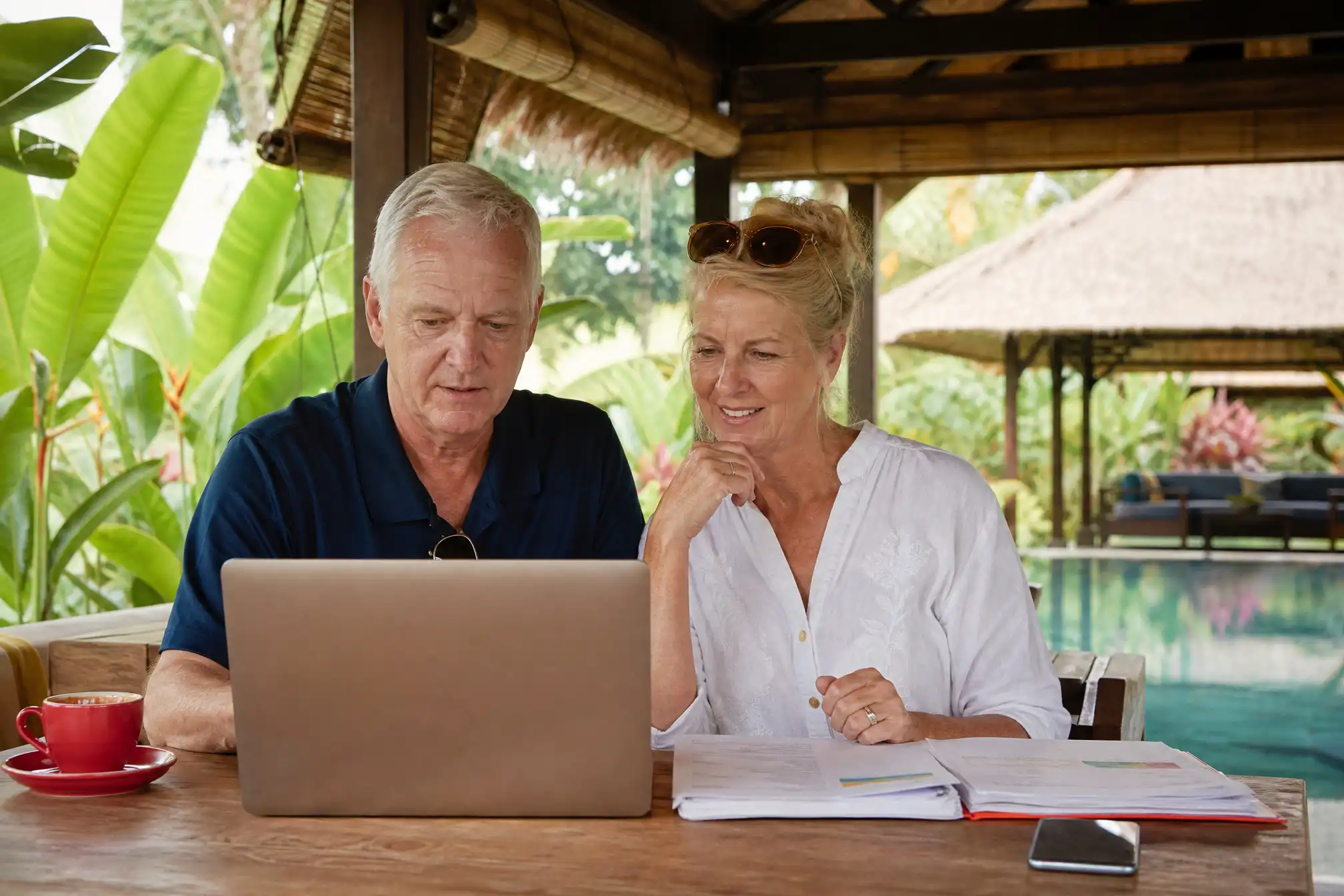 Australian retired couple planning visas at a Bali villa with laptop