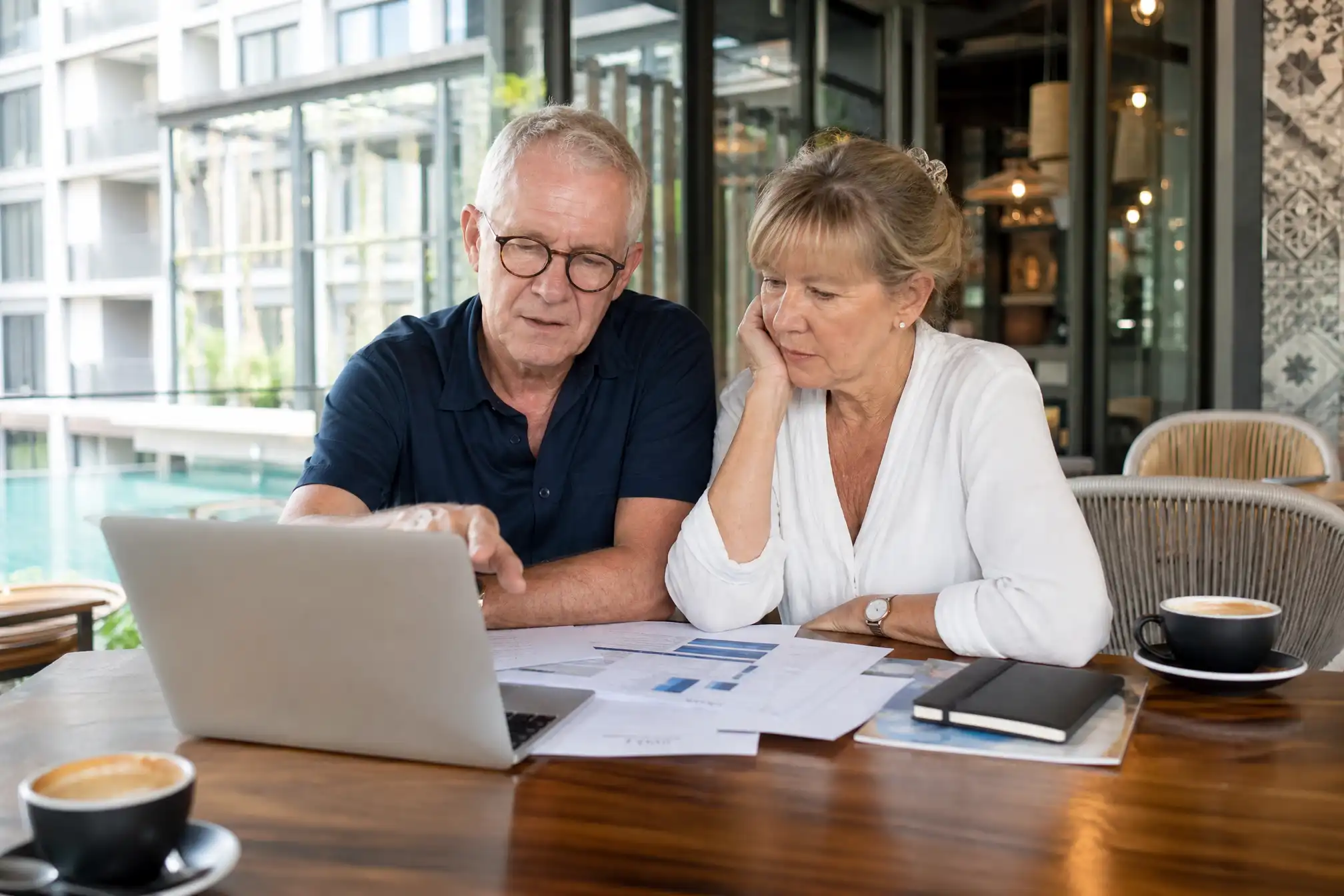 Australian retired couple planning visas at a Thai cafe with laptop